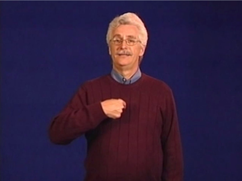 Man standing depicting a sign langage expression, his hand is raised in and pointing to closely to his chest