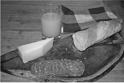 photo of cheese, meat, and bread on cutting board with a glass of juice